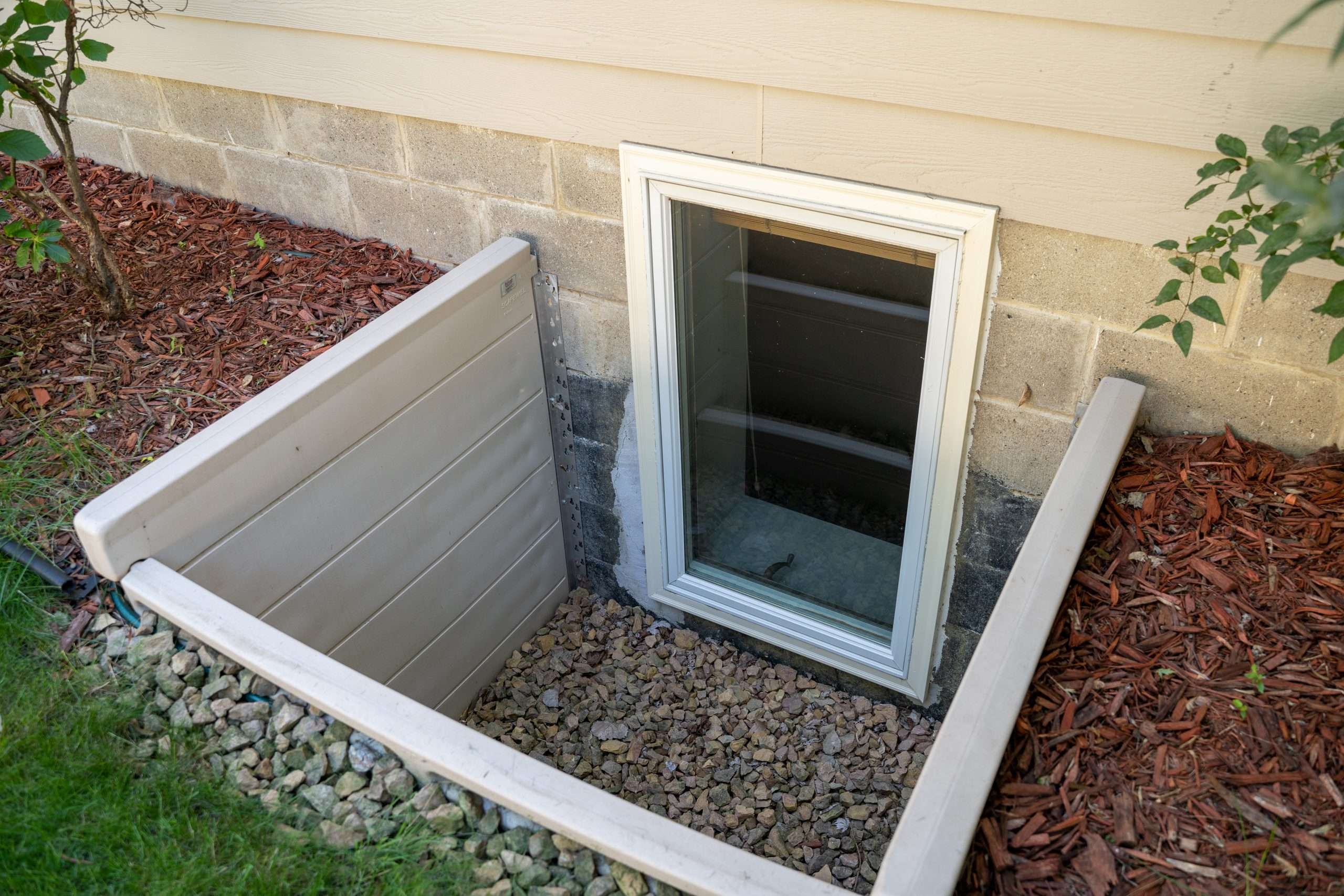 Exterior view of an egress window in a basement bedroom. These windows are required as part of the USA fire code for basement bedrooms Egress Windows | Replace Basement Windows | Complete Basement Systems | Long Island, NY